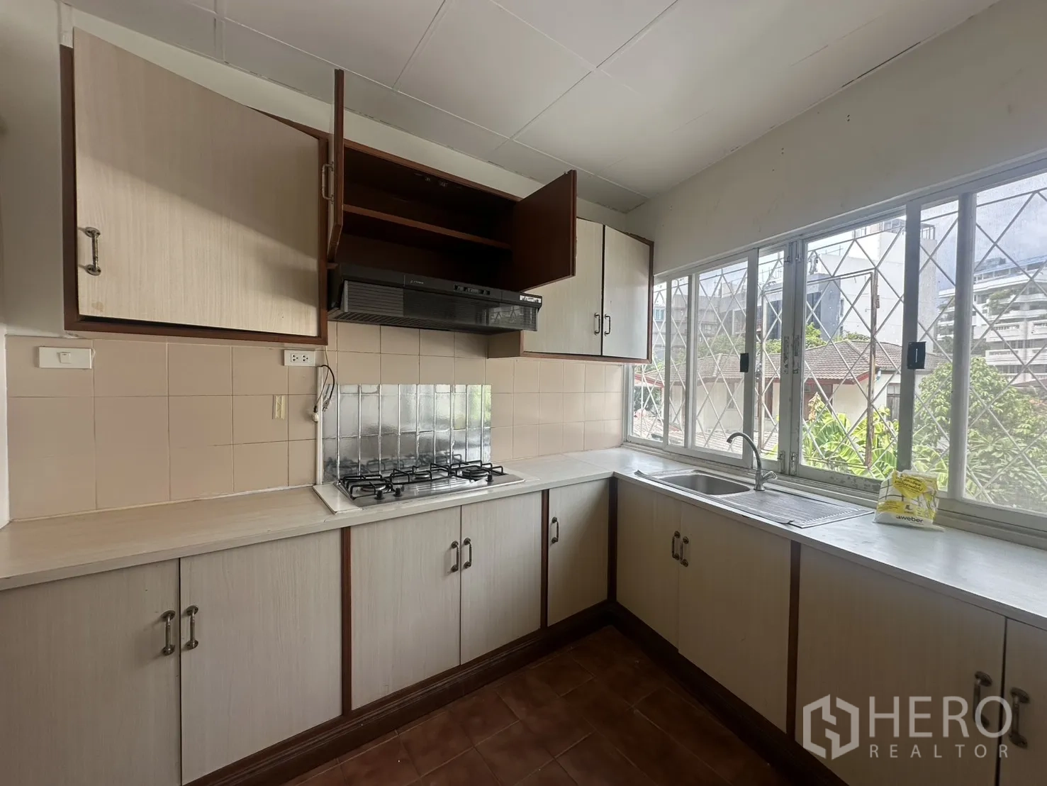 Home Office for rent in Watthana, Bangkok - Corner kitchen with range hood, sink, and storage under bright windows.