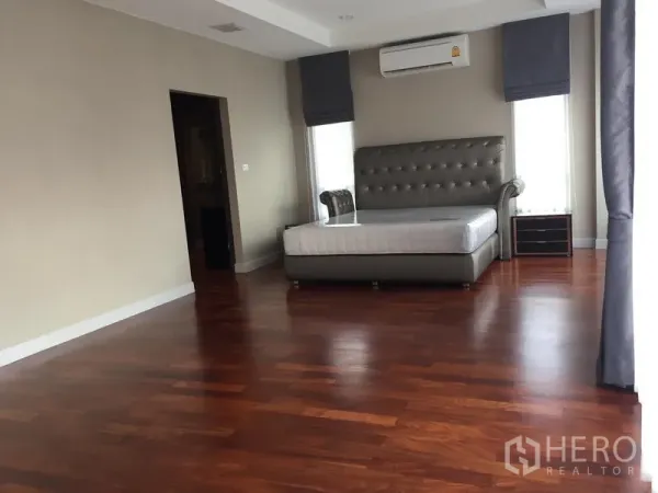 Detached House for rent or sale in Saphan Sung, Bangkok - Spacious master bedroom with polished wood floors and upholstered bed frame.
