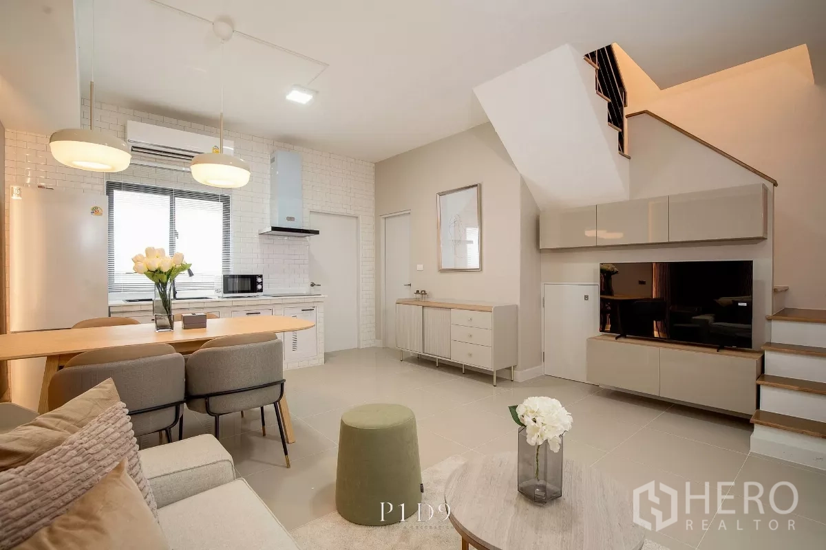 Townhouse for rent in Bang Phli, Samut Prakan - Open‑plan lounge with kitchen, dining bar, staircase and built‑in TV cabinet