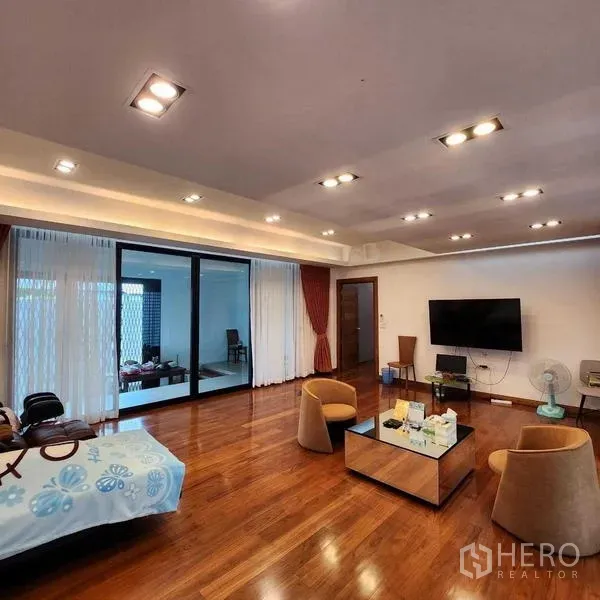 บ้าน ขายในPhra Khanong, Bangkok - ห้องนั่งเล่นกว้าง พื้นไม้เงางาม ไฟดาวน์ไลท์ และทีวีติดผนัง