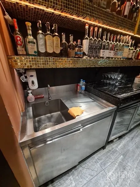 零售空间 出租在Bang Rak, Bangkok - 黑色大理石吧台，整齐酒瓶陈列与高挑金色网格顶。