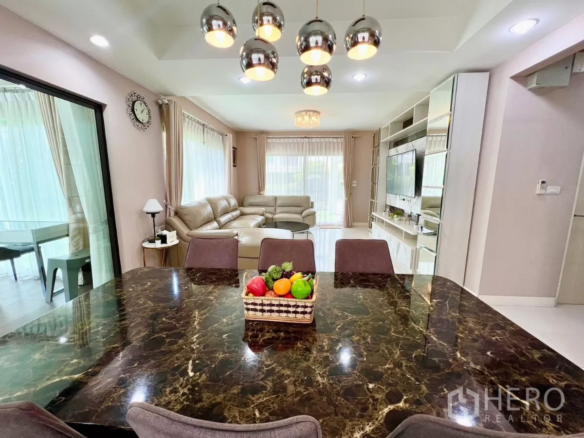 Detached House for rent or sale in Bang Phli, Samut Prakan - View from dining to lounge showing marble-top table and built-in media wall.
