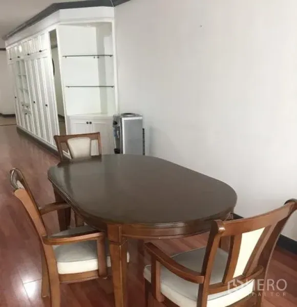 Condominium for rent in Watthana, Bangkok - Dining area with wooden oval table, four chairs, built-in white cabinetry and polished wood floors.