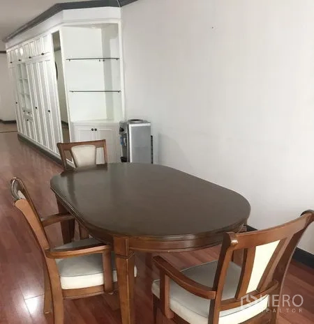 Condominium for rent in Watthana, Bangkok - Dining area with wooden oval table, four chairs, built-in white cabinetry and polished wood floors.