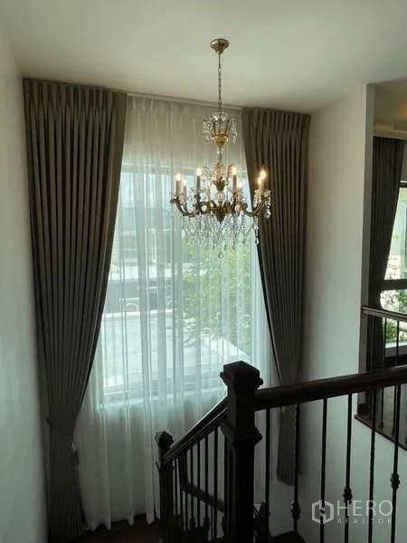 บ้าน ให้เช่าหรือขายในLat Krabang, Bangkok - โถงบันไดหน้าต่างสูง ผ้าม่านทิ้งตัว และโคมแชนเดอเลียร์กับราวไม้