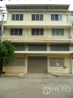 โรงงาน for rent in Thung Khru, Bangkok - ด้านหน้าอาคารโรงงานสูงหลายชั้นพร้อมประตูม้วนและช่องลมบานเกล็ด.