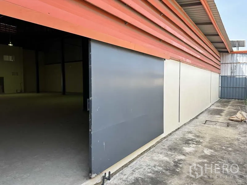 โรงงาน ขายในMueang Samut Prakan, Samut Prakan - ประตูเหล็กบานเลื่อนด้านข้างโกดังติดทางเดินคอนกรีต
