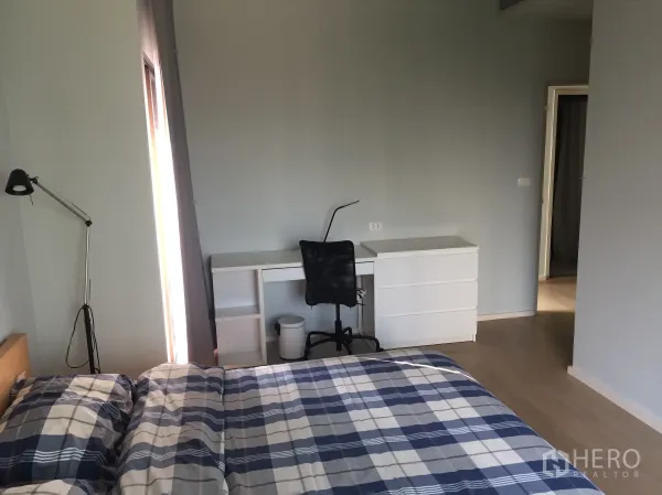 คอนโด ให้เช่าในBangkok - ห้องนอนหลักกว้าง พร้อมโต๊ะทำงาน เก้าอี้ และหน้าต่างบานใหญ่ พื้นไม้สีอ่อน