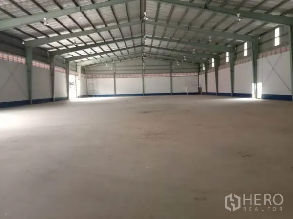 Warehouse for rent in Sai Noi, Nonthaburi - Spacious high-ceiling warehouse interior with steel truss roof and open clear-span floor.