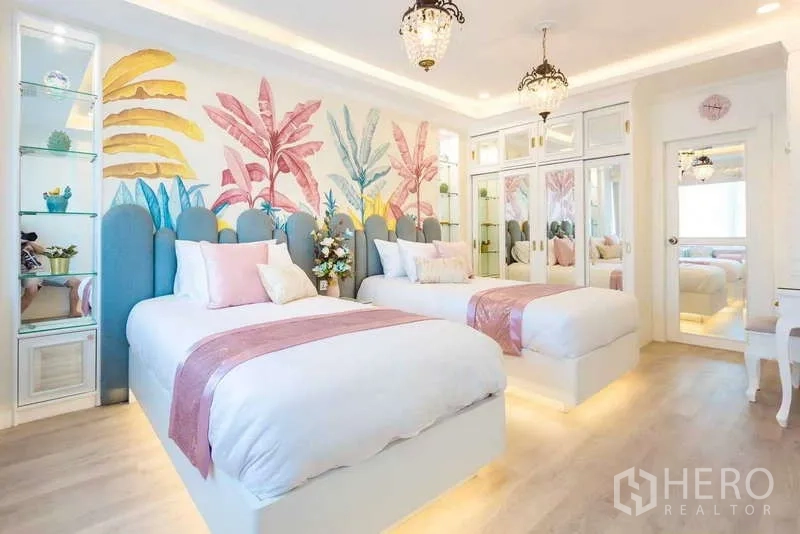 Townhouse for rent in Lat Phrao, Bangkok - Twin bedroom with two single beds, pastel botanical mural and mirrored wardrobes.