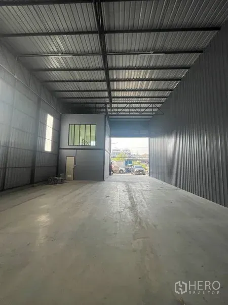 Warehouse for rent in Bang Kapi, Bangkok - High-clearance warehouse interior with steel roof trusses, concrete floor and a mezzanine office.