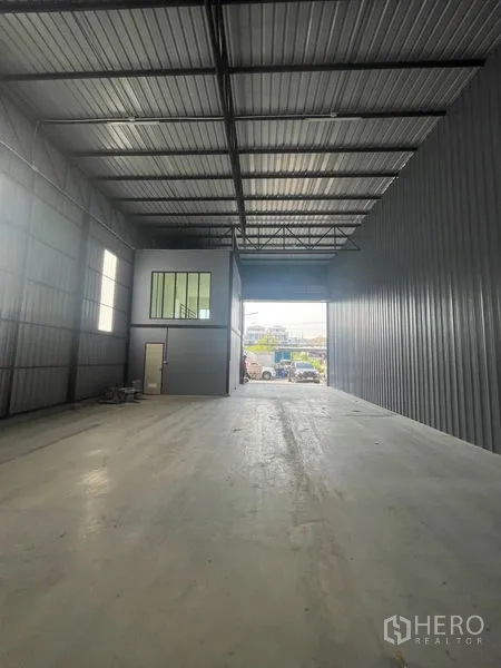 Warehouse for rent in Bang Kapi, Bangkok - High-clearance warehouse interior with steel roof trusses, concrete floor and a mezzanine office.
