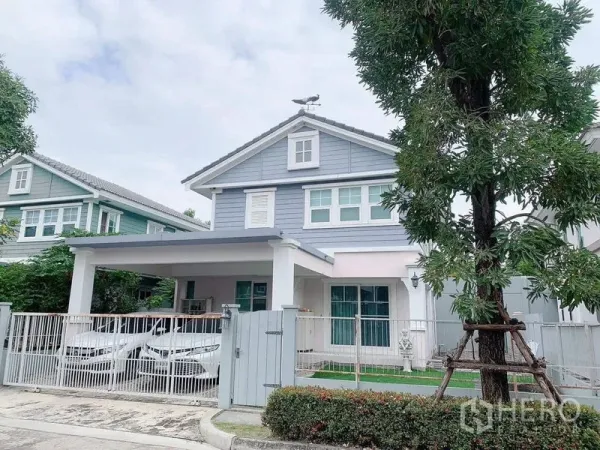 独立式住宅 出租或出售在Bang Phli, Samut Prakan - 房屋正面另一角度，展示可停两车的遮蔽车位与白色栅栏草坪