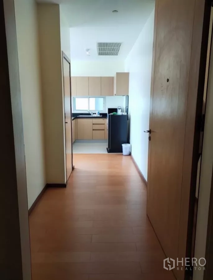 Condominium for rent in Chatuchak, Bangkok - Entry hallway leading to a built-in kitchen with fridge and cabinets.