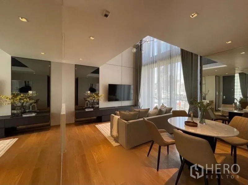 คอนโด ให้เช่าในKhlong Toei, Bangkok - มุมทานอาหารและโซฟาพร้อมผนังกระจกเงา พื้นไม้ และผ้าม่านสูง