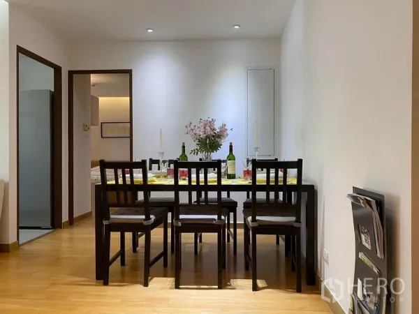 Condominium for rent or sale in Phra Khanong, Bangkok - Dining area with six-seat wooden table, recessed lighting and flower centerpiece.