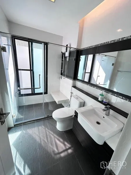 Detached House for rent or sale in Prawet, Bangkok - Second bathroom with glass shower, wide mirror, and natural light.