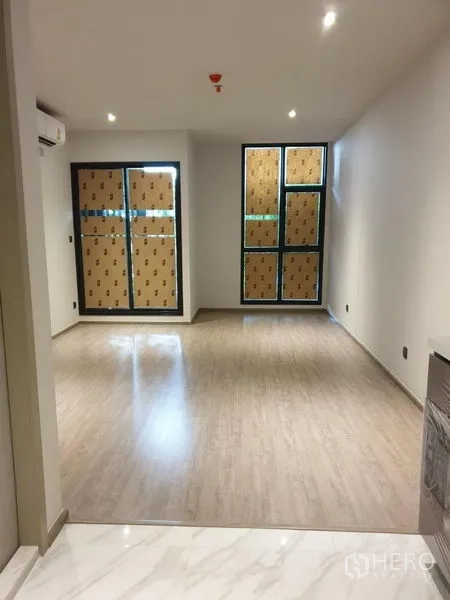 Condominium for sale in Watthana, Bangkok - Open-plan living space with wide windows, recessed lighting and light timber floors.