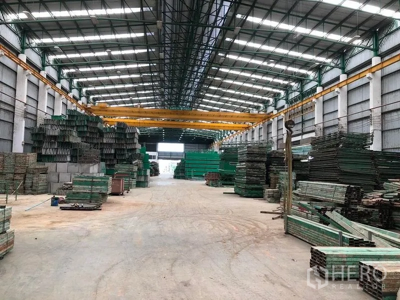 工厂 出租或出售在Lat Lum Kaeo, Pathum Thani - 长通道仓库，配多台门式行车与整齐堆放的材料。