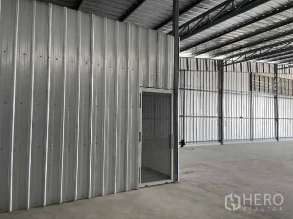 Warehouse for rent in Min Buri, Bangkok - Side view of warehouse wall with glass door and steel columns.
