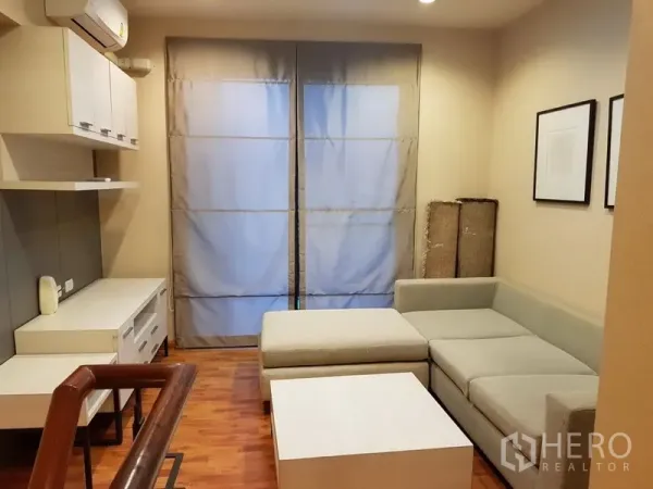 联排别墅 出租在Phra Khanong, Bangkok - 楼上起居室，L形沙发、茶几、木地板与大窗帘