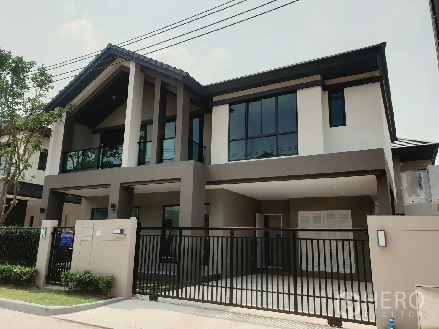 บ้านเดี่ยว for rent in Saphan Sung, Bangkok - ด้านหน้าบ้านเดี่ยวสไตล์โมเดิร์นสองชั้น พร้อมโรงจอดรถและระเบียงกระจก.