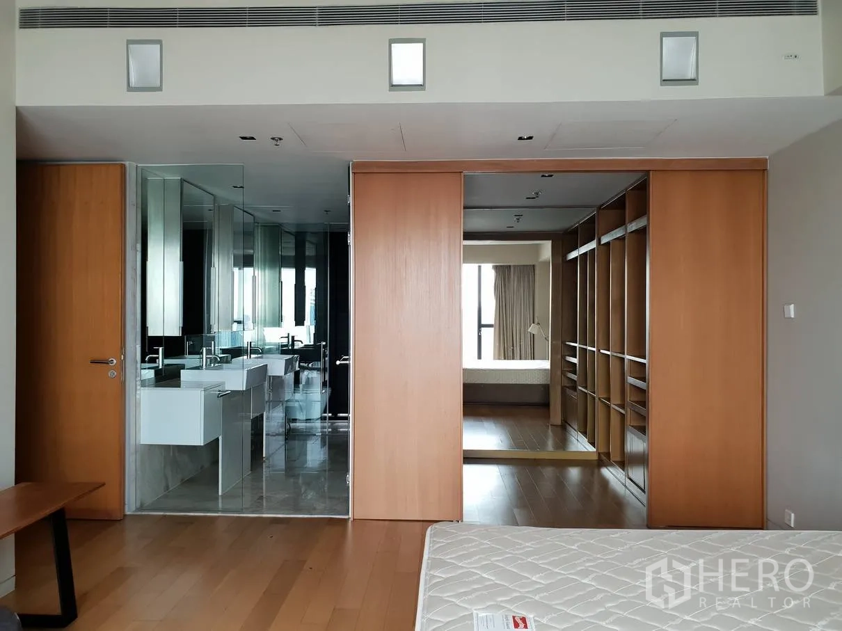 Condominium for rent in Sathon, Bangkok - Master suite corridor with sliding wooden doors leading to a glass-walled bathroom and a walk-in closet.