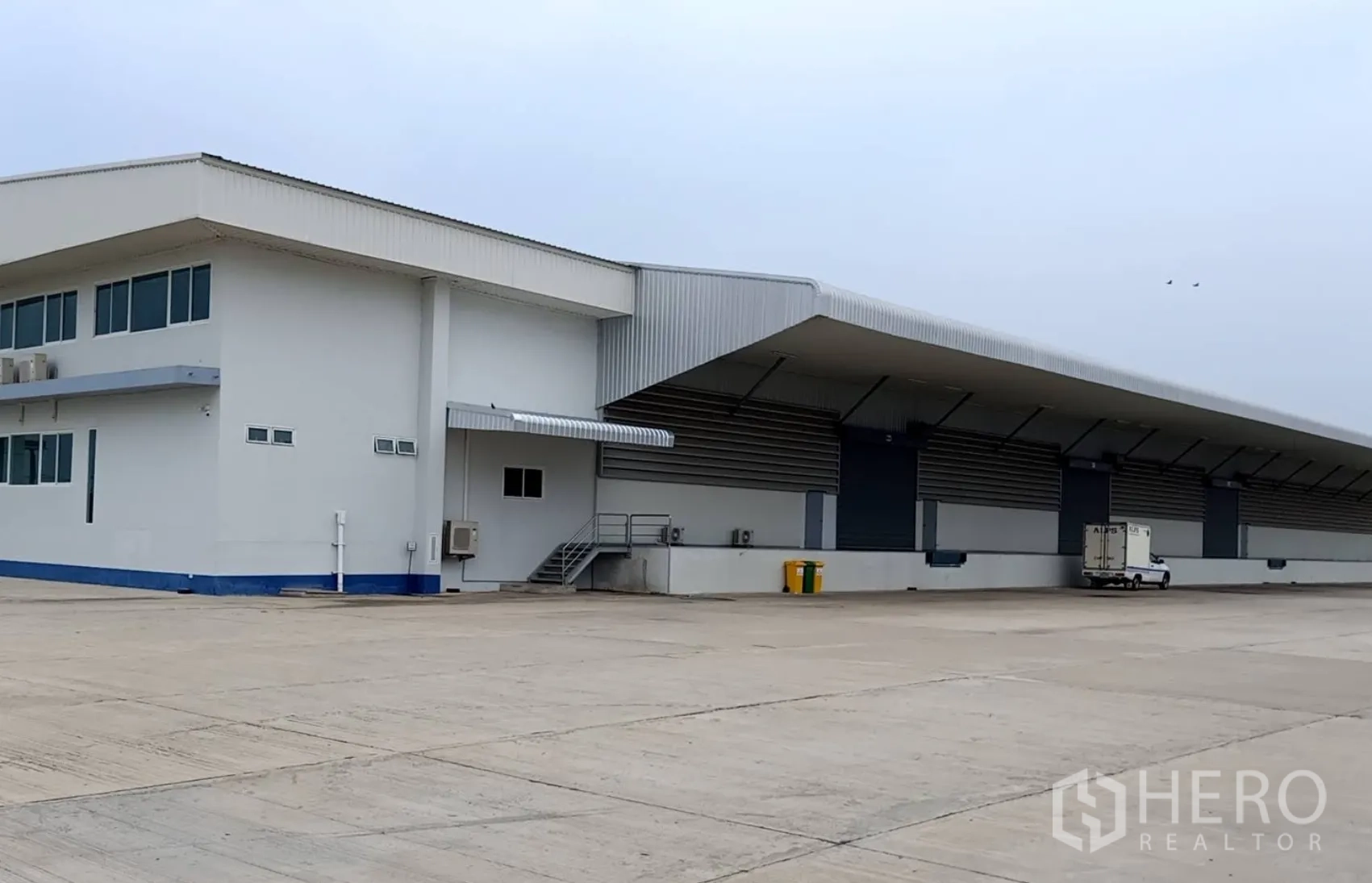 Warehouse for rent in Wang Noi, Phra Nakhon Si Ayutthaya - Warehouse exterior with attached office block, external stairs, and a large concrete yard for truck access.