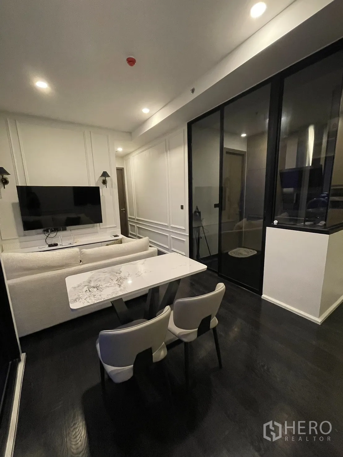 Condominium for rent in Watthana, Bangkok - Dining table for two next to the TV wall and glass partition.
