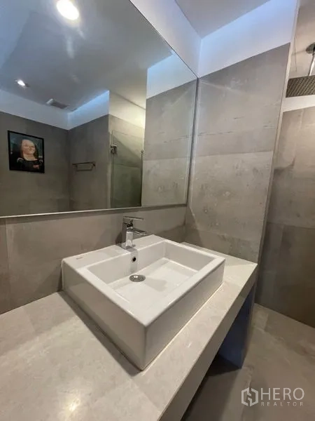 Townhouse for rent in Khlong Toei, Bangkok - Contemporary vanity with square basin and wide mirror in grey-tone bathroom.