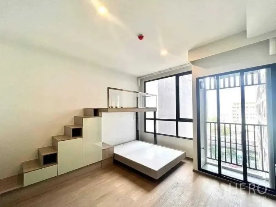 Condominium for sale - Sunlit bedroom with platform bed and storage steps facing floor-to-ceiling windows and a balcony.