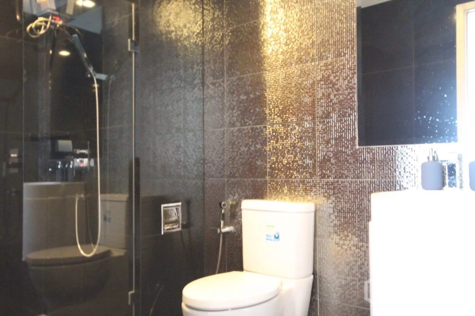 Condominium for rent in Khlong Toei, Bangkok - Modern bathroom with glass-enclosed shower, mosaic feature wall, toilet and vanity.