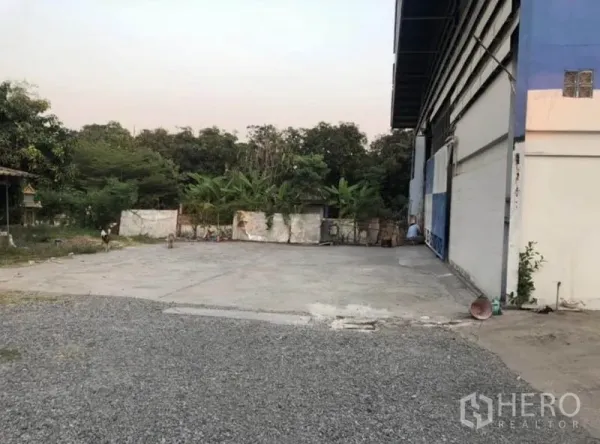 货栈 出租在Bang Phli, Samut Prakan - 仓库侧的宽阔混凝土与碎石院子，后方绿化。
