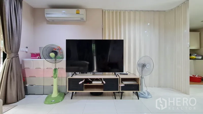 独立式住宅 出售在Samut Prakan - 客厅影音墙，超大电视、电视柜与空调。