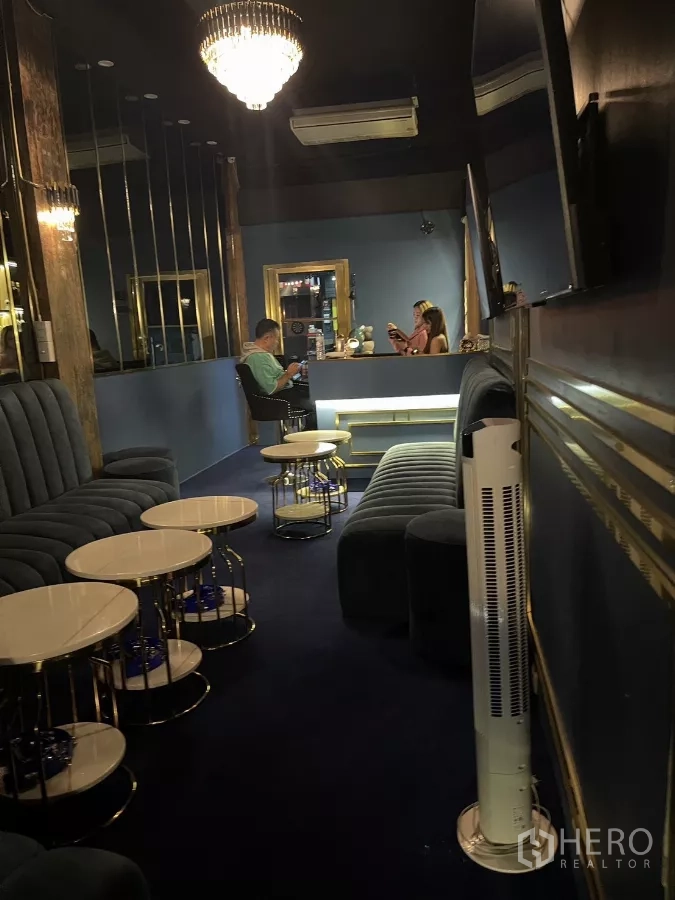 店屋 出租在Watthana, Bangkok - 狭长型休闲区，天鹅绒长椅、叠圆桌与中央吊灯。