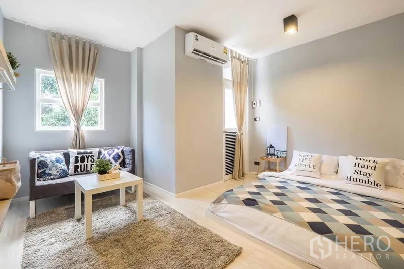 บ้าน ให้เช่าในKhlong Toei, Bangkok - ห้องนอนสีเทาอ่อน เตียงโลว์โปรไฟล์ โซฟาริมหน้าต่าง และพรมฟู