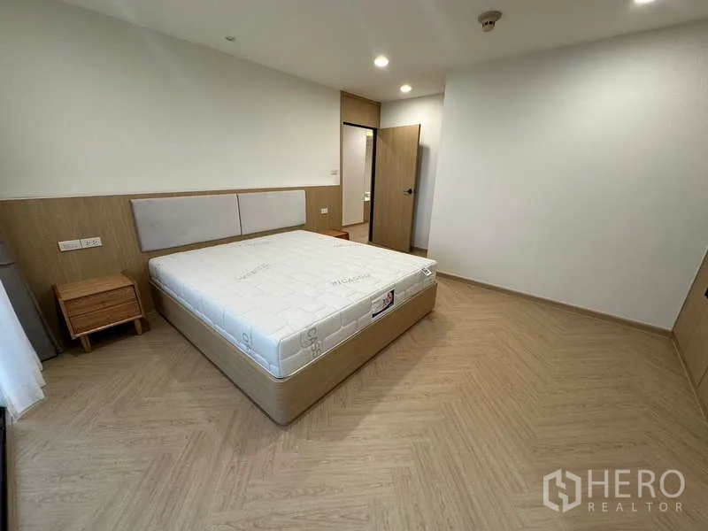 คอนโด ให้เช่าในWatthana, Bangkok - ห้องนอนที่สอง พื้นลายก้างปลา หัวเตียงบุ และโต๊ะข้างเตียง