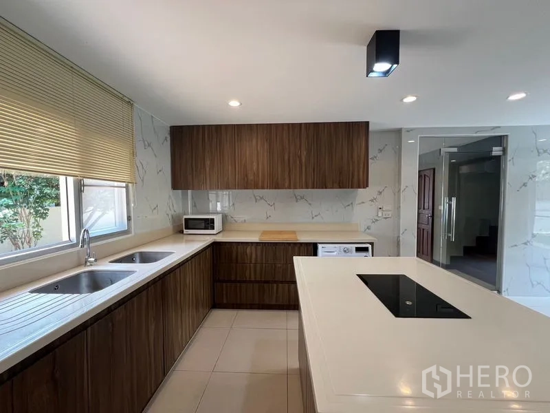 Detached House for sale in Mueang Pathum Thani, Pathum Thani - Kitchen counter with double sink, wood cabinetry and window blinds.