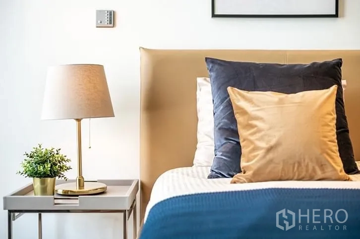 คอนโด ให้เช่าในBang Rak, Bangkok - มุมโต๊ะข้างเตียง โคมไฟ และหมอนบนเตียงบุผ้า