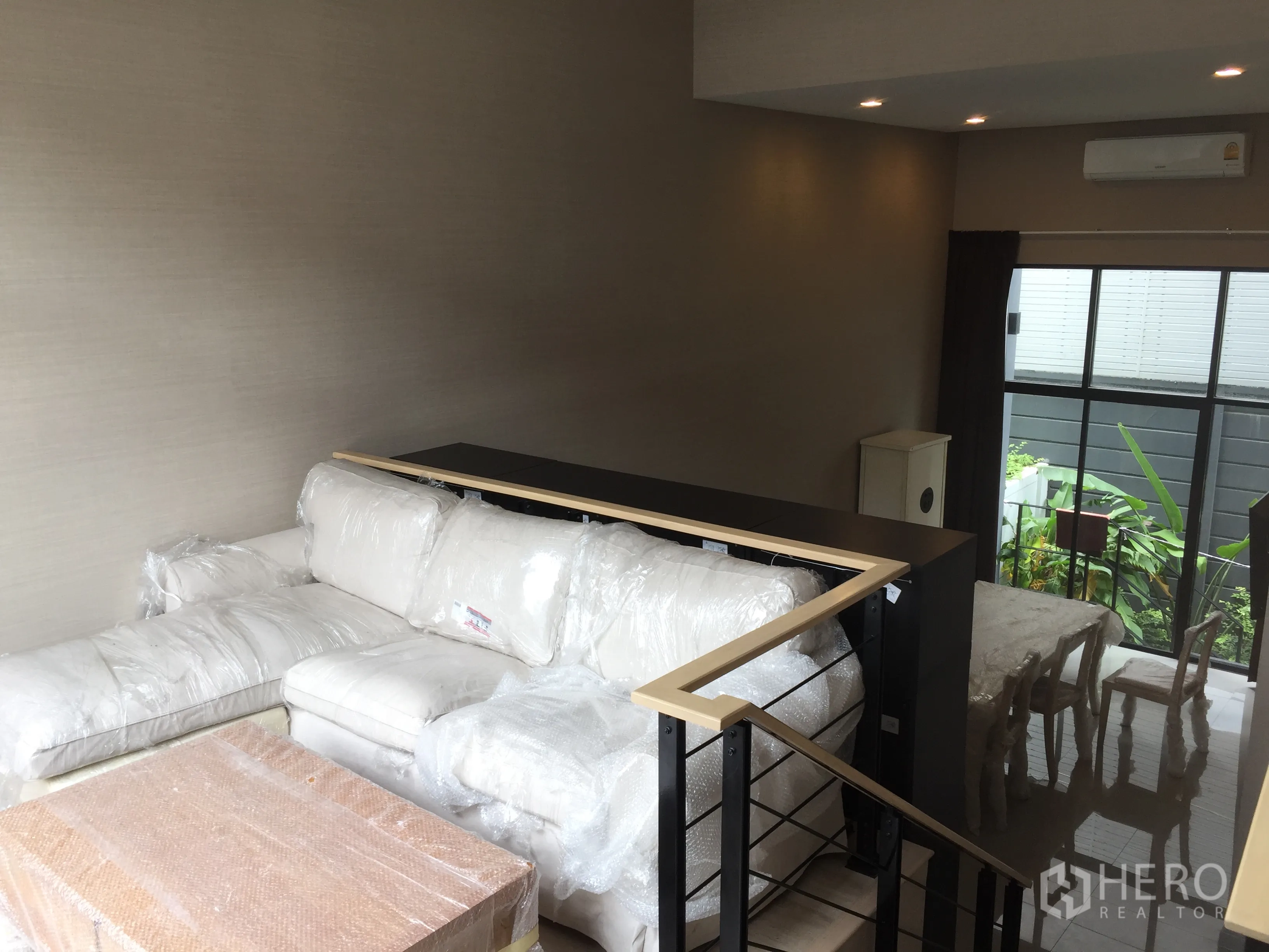 ทาวน์เฮาส์ ให้เช่าในSuan Luang, Bangkok - ชั้นลอยนั่งเล่น โซฟาเข้ามุม เพดานสูง พร้อมไฟดาวน์ไลท์และกระจกสูงมองเห็นสวน