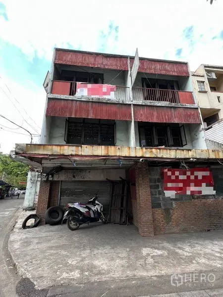 Shophouse for rent or sale in Bang Khen, Bangkok - Front facade of twin-unit shophouse showing balconies and closed shopfronts.