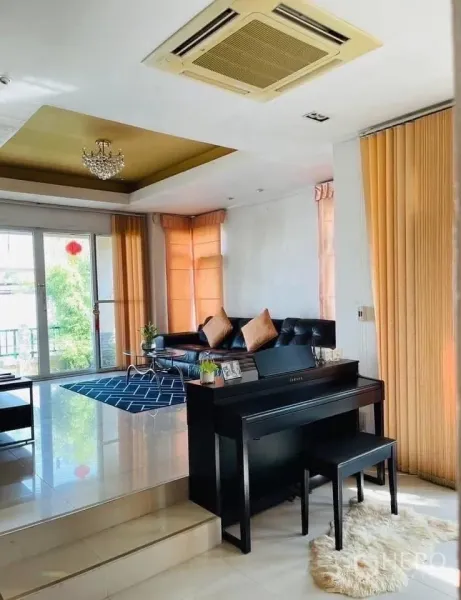 独立式住宅 出租或出售在Lam Luk Ka, Pathum Thani - 采光充足的起居区，推拉落地门、天花机空调与钢琴。