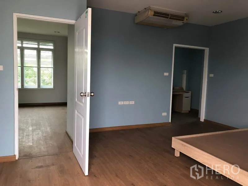 独立式住宅 出售在Bang Khen, Bangkok - 主卧角度，大窗采光好，通往相邻房间的门与木地板。