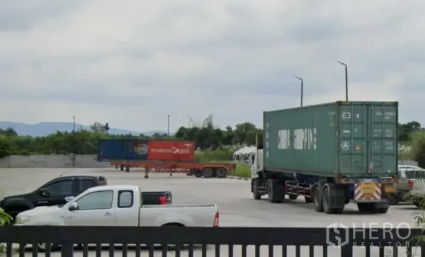 货栈 出租在Si Racha, Chon Buri - 春武里诗丽叻工业仓库场地内的宽阔混凝土硬地，停有集装箱卡车与拖车。