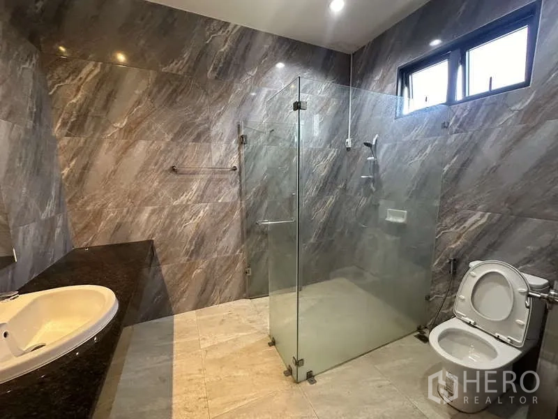 Factory for rent in Lam Luk Ka, Pathum Thani - Modern bathroom with glass-enclosed shower, vanity and toilet.