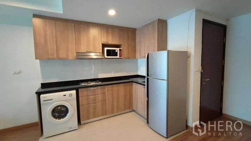 คอนโด ให้เช่าในKhlong Toei, Bangkok - ครัวบิวท์อินตู้ไม้ เคาน์เตอร์สีดำ พร้อมตู้เย็น ไมโครเวฟ และเครื่องซักผ้า