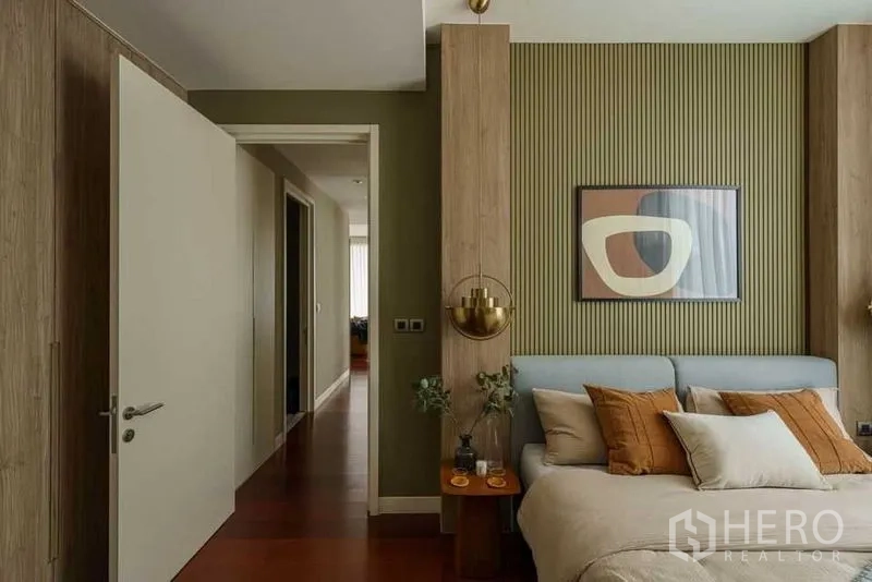 公寓 出租在Watthana, Bangkok - 主卧入口视角，纹理墙板、温润木地板与黄铜壁灯。
