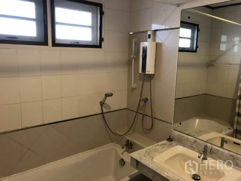 Detached House for rent - Bathroom with bathtub, handheld shower, water heater and wide mirror.