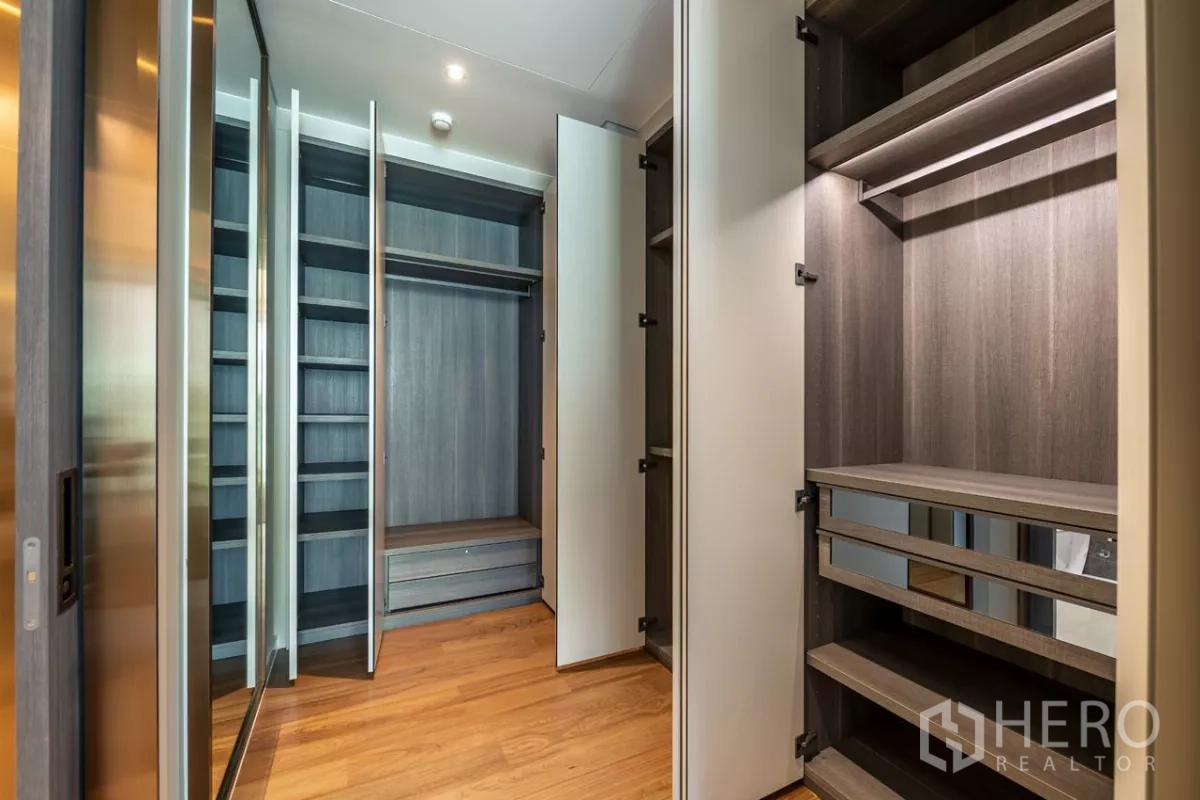 Condominium for rent or sale in Pathum Wan, Bangkok - Walk-in closet with open shelving, drawers and hanging space in wood finish.