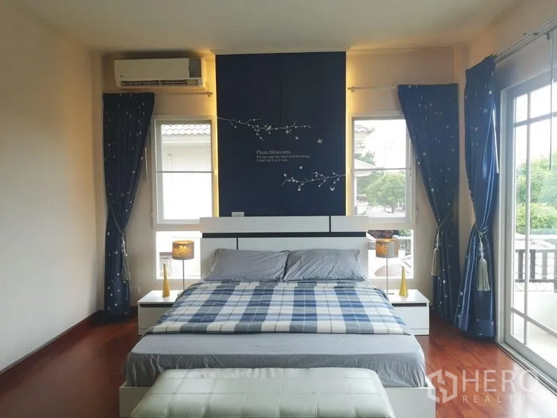 บ้าน ให้เช่า - ห้องนอนหลักกว้าง ผนังตกแต่งสีน้ำเงิน หน้าต่างเต็มบาน มีระเบียง และพื้นไม้จริง